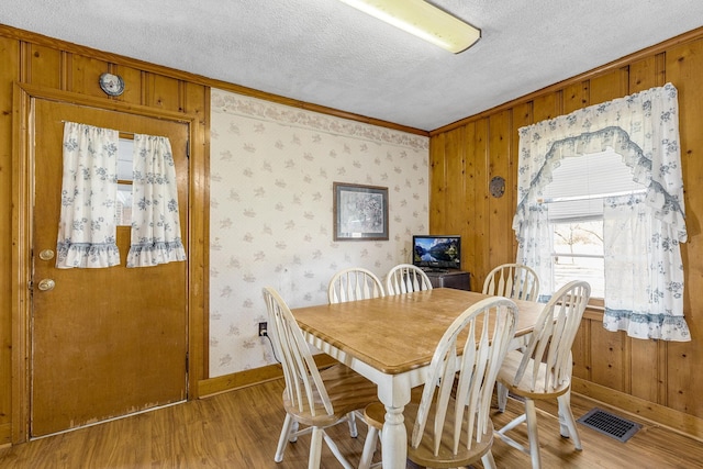 dining room with crown molding, wood-type flooring, and a textured ceiling