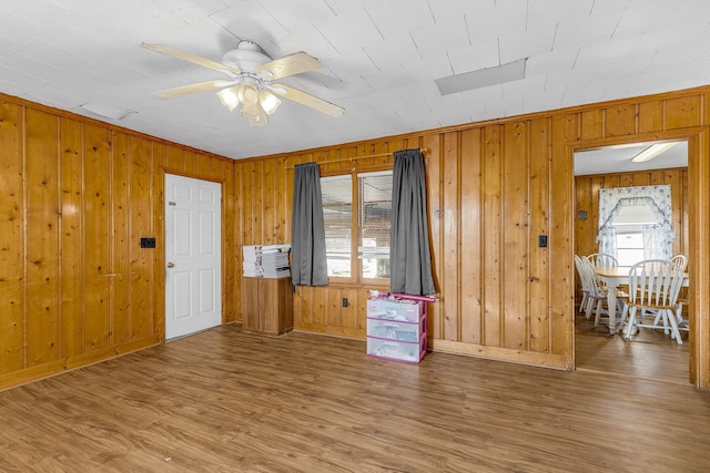 interior space with hardwood / wood-style floors, ceiling fan, and wood walls