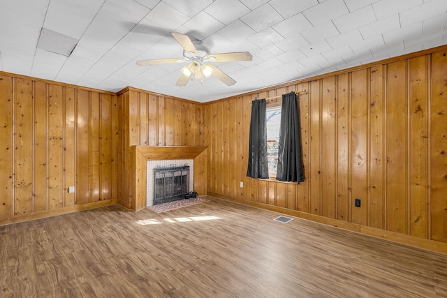 unfurnished living room featuring hardwood / wood-style floors, a brick fireplace, and ceiling fan