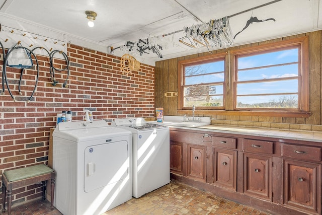 laundry area with a healthy amount of sunlight, separate washer and dryer, and brick wall