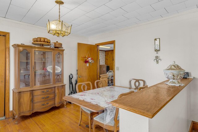 dining space with light wood-type flooring, crown molding, and a chandelier