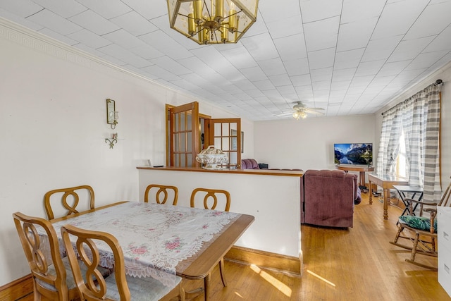 dining space with crown molding, ceiling fan with notable chandelier, and hardwood / wood-style flooring