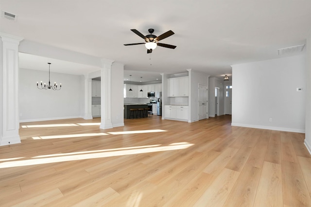 unfurnished living room with ceiling fan with notable chandelier, ornate columns, and light wood-type flooring