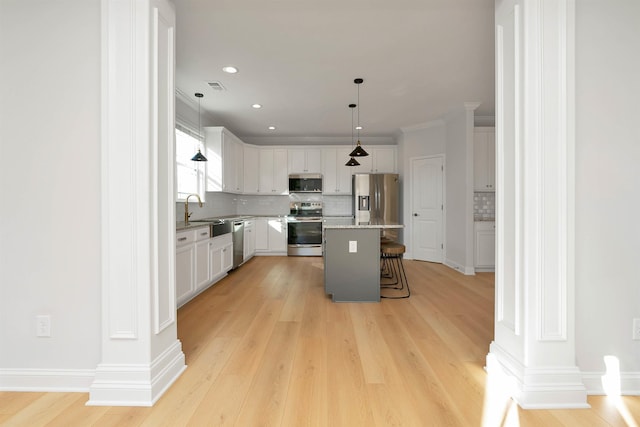 kitchen featuring a center island, decorative backsplash, white cabinets, appliances with stainless steel finishes, and a kitchen breakfast bar