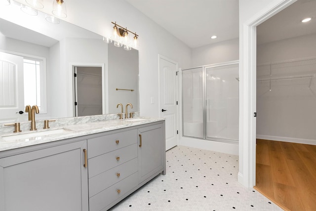 bathroom featuring a shower with door and vanity