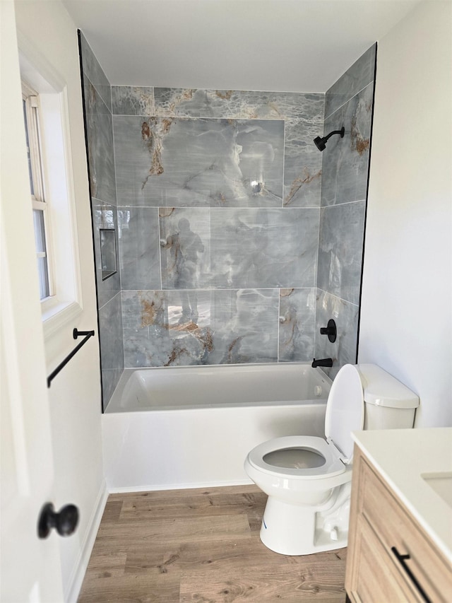 full bathroom featuring hardwood / wood-style flooring, tiled shower / bath combo, vanity, and toilet