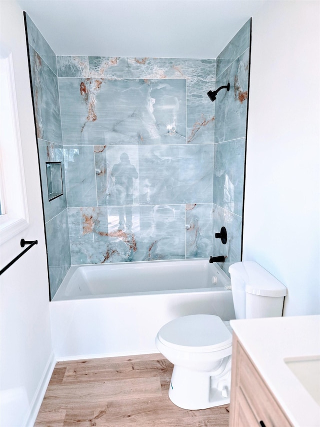 full bathroom featuring hardwood / wood-style flooring, tiled shower / bath combo, vanity, and toilet