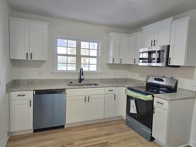 kitchen with light hardwood / wood-style flooring, sink, stainless steel appliances, and white cabinets