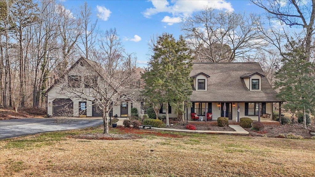 new england style home featuring a garage, a porch, and a front lawn