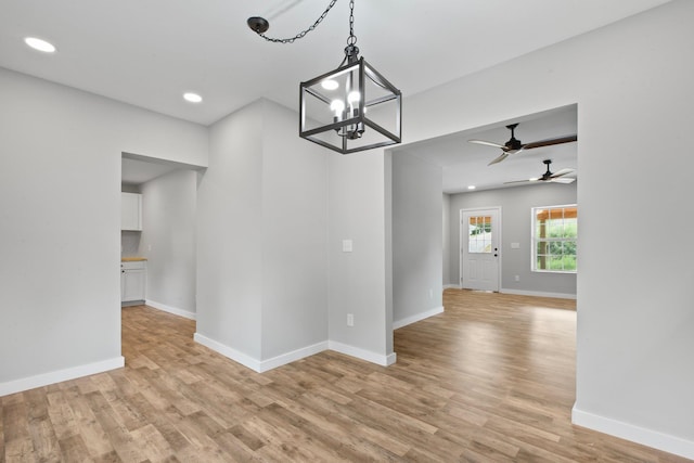 interior space featuring ceiling fan with notable chandelier and light hardwood / wood-style flooring