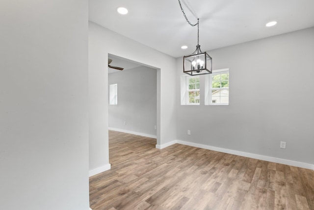 unfurnished dining area with a chandelier and hardwood / wood-style floors