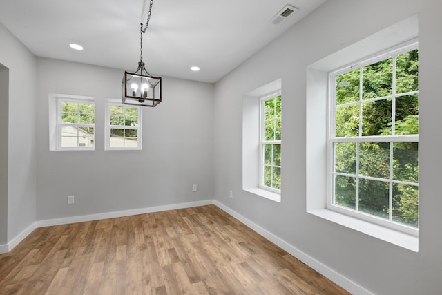 unfurnished dining area with a notable chandelier and hardwood / wood-style flooring