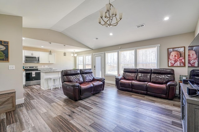 living room featuring light wood-type flooring, lofted ceiling, and a chandelier