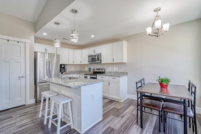 kitchen featuring stainless steel appliances, white cabinets, and pendant lighting