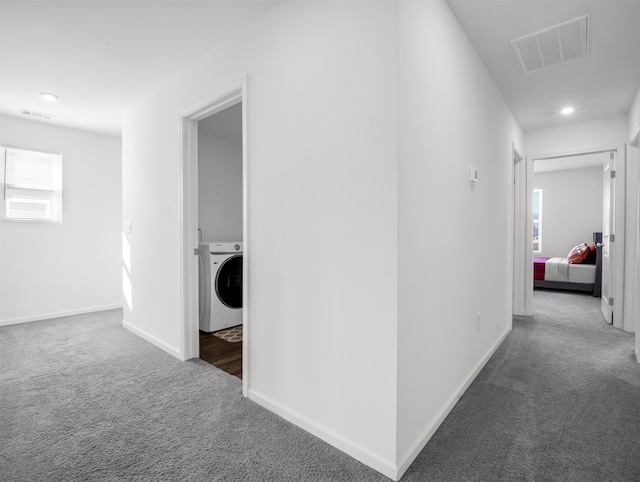 hall featuring washer / dryer and dark colored carpet