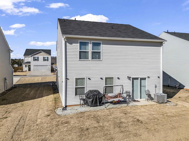 rear view of house featuring cooling unit, a patio, a lawn, and a garage