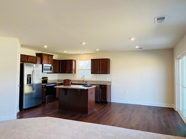 kitchen with stainless steel appliances, a center island, a wealth of natural light, and a breakfast bar area