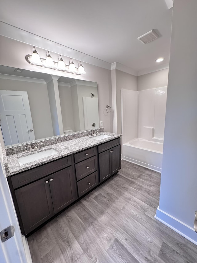 bathroom with ornamental molding, vanity, hardwood / wood-style floors, and washtub / shower combination