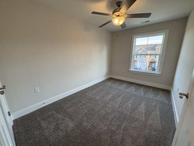 empty room with ceiling fan and dark colored carpet