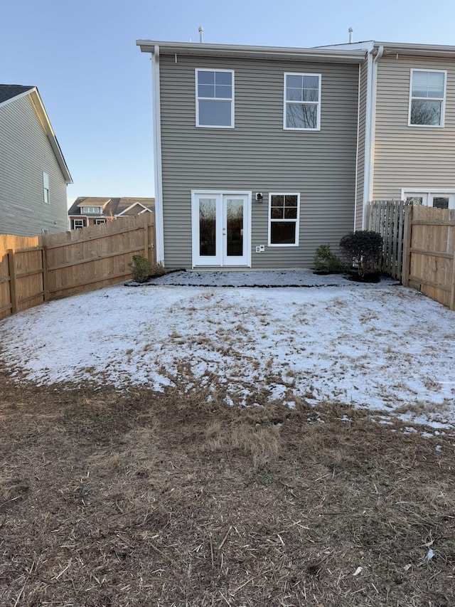 snow covered back of property with french doors