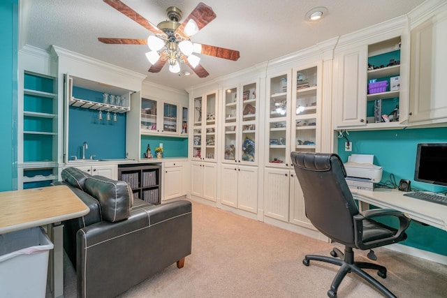 carpeted office featuring a textured ceiling, beverage cooler, crown molding, ceiling fan, and sink