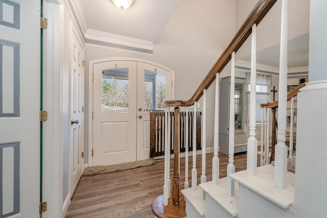 entrance foyer with wood-type flooring, a textured ceiling, french doors, and crown molding