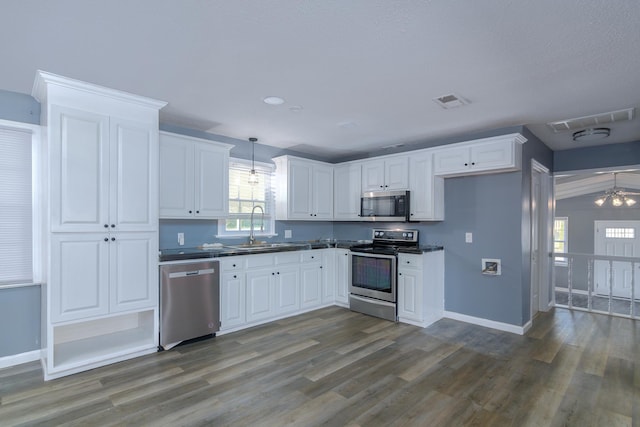 kitchen featuring sink, stainless steel appliances, white cabinetry, and hanging light fixtures