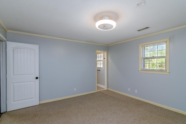 spare room featuring crown molding, a wealth of natural light, and carpet