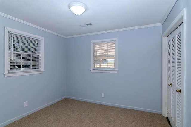 unfurnished bedroom with ornamental molding, a closet, and carpet floors