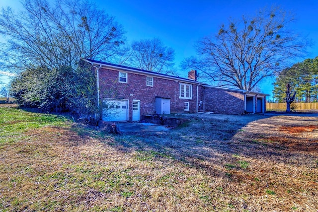 back of house featuring a lawn and a garage