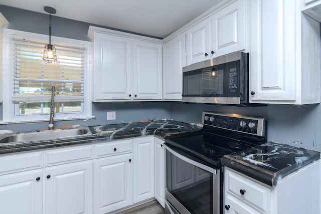 kitchen with sink, white cabinets, hanging light fixtures, and appliances with stainless steel finishes