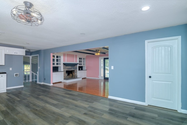 unfurnished living room featuring a fireplace, a textured ceiling, a healthy amount of sunlight, and dark hardwood / wood-style floors