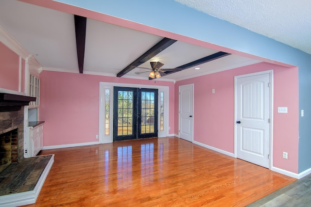 unfurnished living room featuring beamed ceiling, french doors, ornamental molding, ceiling fan, and light hardwood / wood-style floors