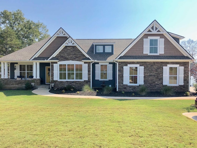 craftsman house with stone siding, roof with shingles, and a front yard