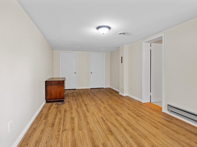 unfurnished room featuring a baseboard heating unit and light wood-type flooring