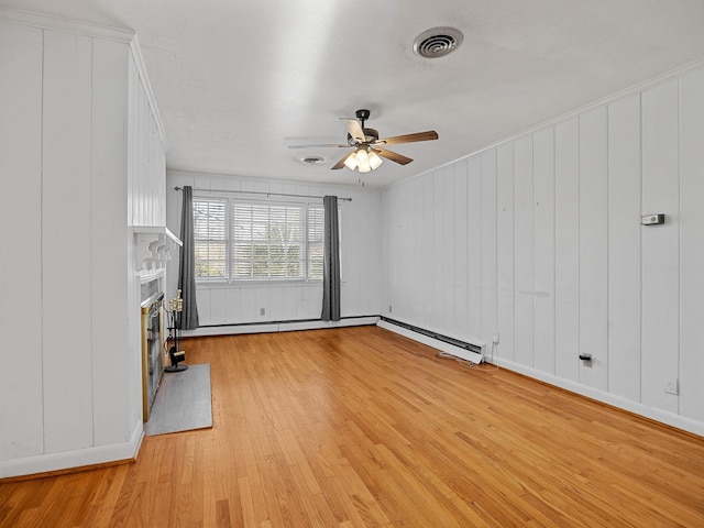 unfurnished living room featuring wood walls, crown molding, ceiling fan, light hardwood / wood-style flooring, and a baseboard radiator