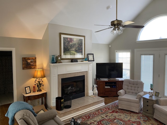 living room featuring vaulted ceiling, hardwood / wood-style flooring, ceiling fan, and a tile fireplace