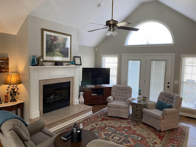 living room with ceiling fan, a tile fireplace, vaulted ceiling, and hardwood / wood-style flooring