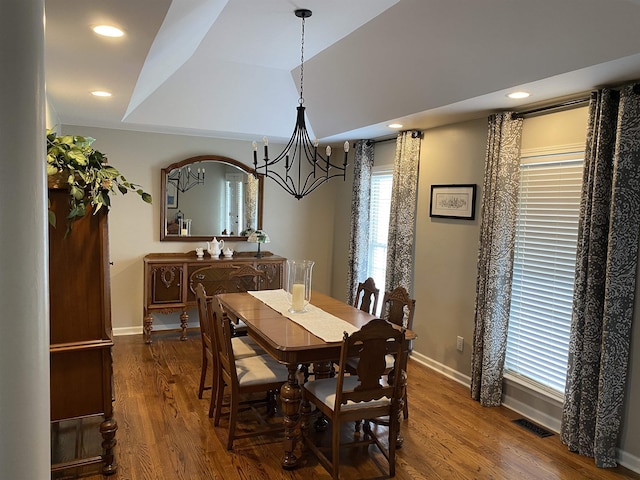 dining space featuring dark wood-type flooring and an inviting chandelier