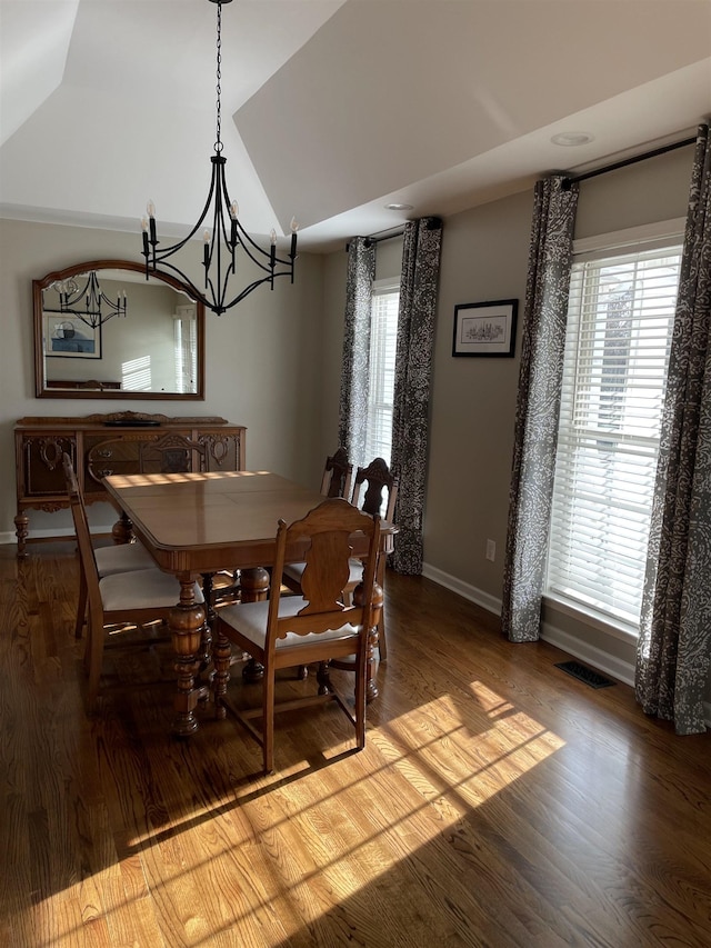 dining area featuring hardwood / wood-style flooring, vaulted ceiling, a chandelier, and plenty of natural light