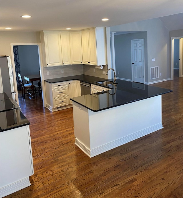 kitchen featuring kitchen peninsula, decorative backsplash, white cabinetry, appliances with stainless steel finishes, and sink