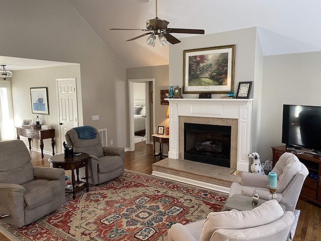 living room with high vaulted ceiling, a tiled fireplace, ceiling fan, and dark hardwood / wood-style floors