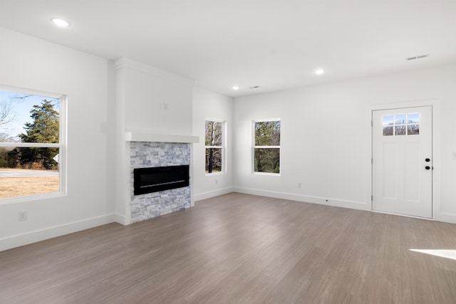 unfurnished living room with a fireplace, light hardwood / wood-style floors, and plenty of natural light