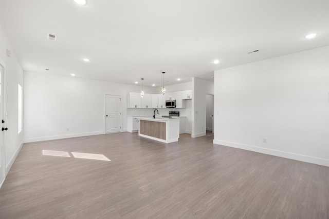 unfurnished living room with light hardwood / wood-style floors and sink