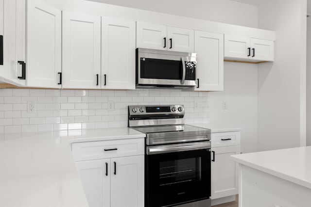 kitchen with white cabinets, appliances with stainless steel finishes, and tasteful backsplash