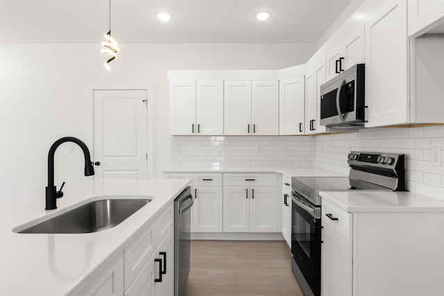 kitchen with appliances with stainless steel finishes, hanging light fixtures, white cabinets, backsplash, and sink