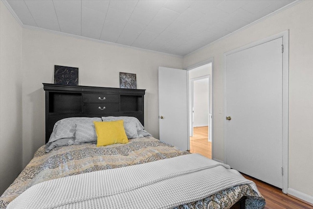 bedroom featuring wood-type flooring and crown molding