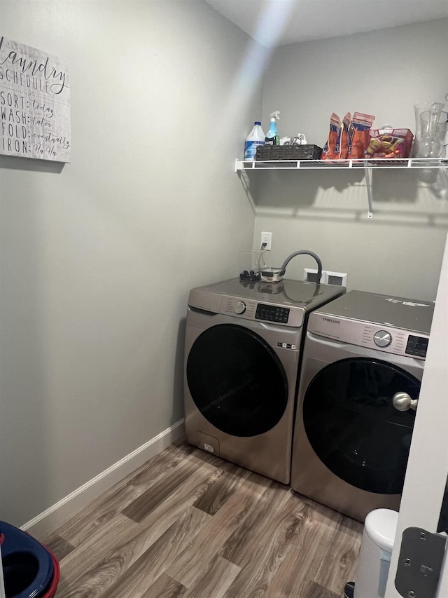 clothes washing area with separate washer and dryer and hardwood / wood-style flooring