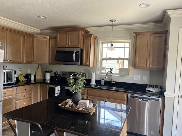 kitchen with dark stone countertops, a kitchen island, sink, hanging light fixtures, and appliances with stainless steel finishes