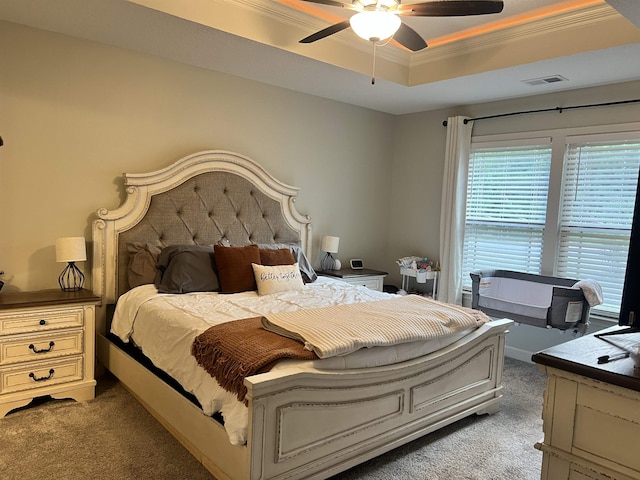 carpeted bedroom with ceiling fan, crown molding, and a raised ceiling